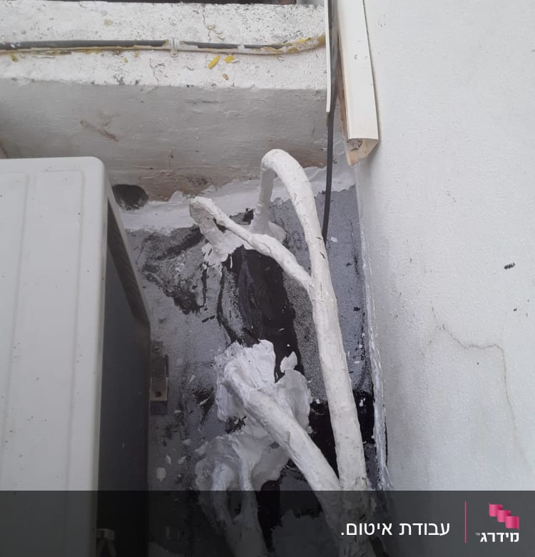 צינורות אטומים בחומר לבן ליד קיר